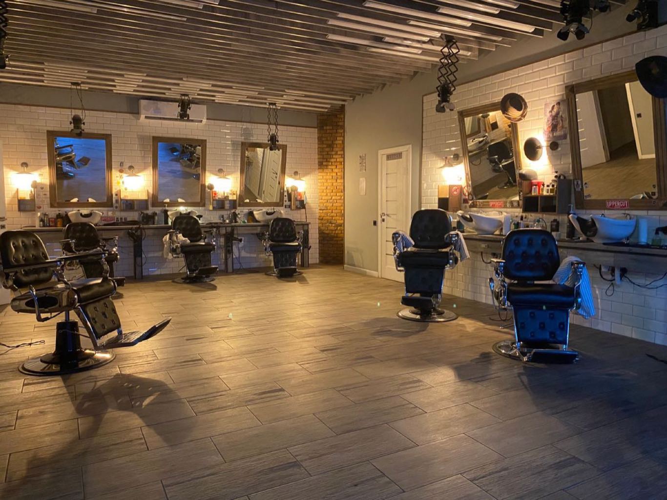 A row of empty barber chairs facing a long mirror