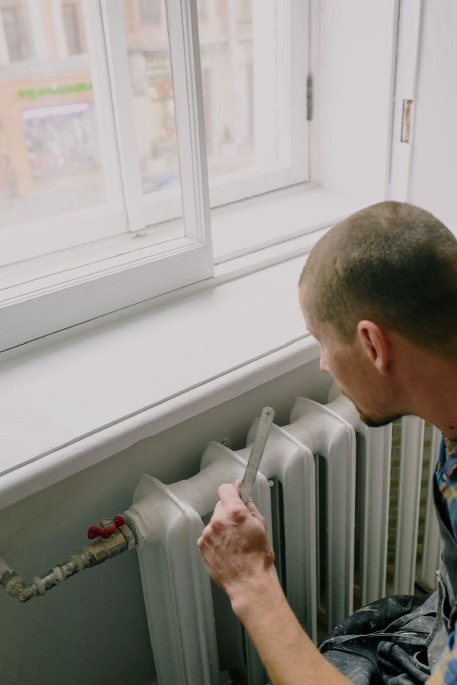 A heating engineer measuring up beside a home heating system